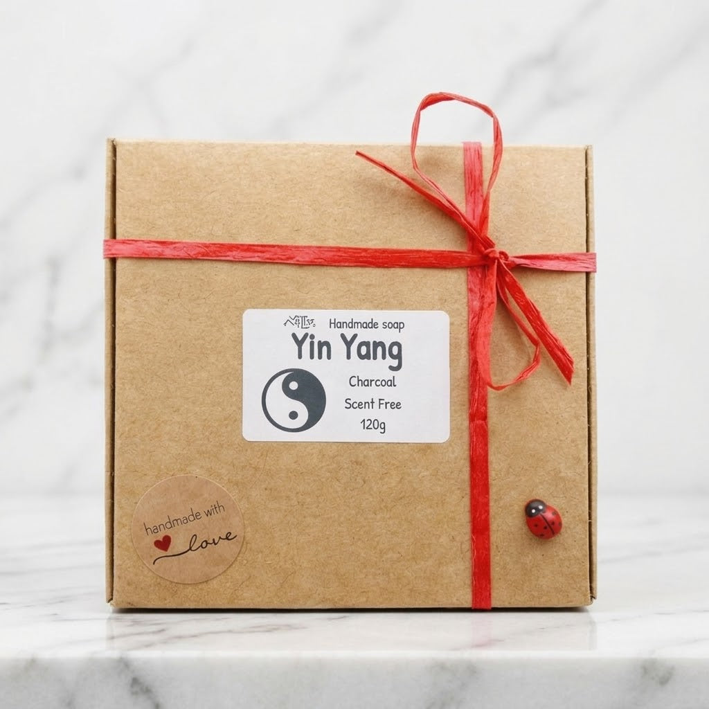 Gift box with a red ribbon and 'Yin Yang' label on a wooden surface with flowers in the background