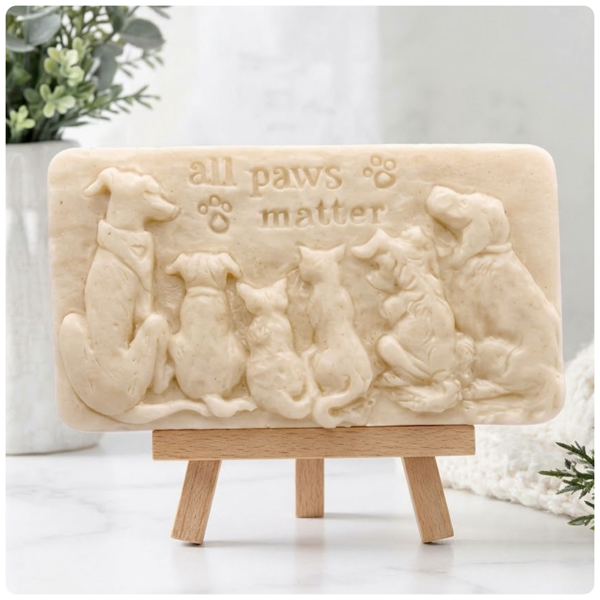 Handmade All Paws Matter vegan soap bar made with yellow French clay and displayed on a wooden easel featuring an embossed pet design.