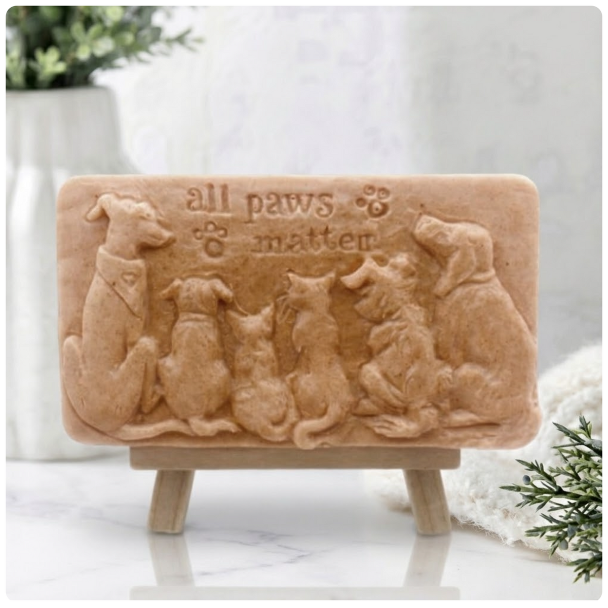 Handmade All Paws Matter vegan soap bar made with red French clay and displayed on a wooden easel featuring an embossed pet design.