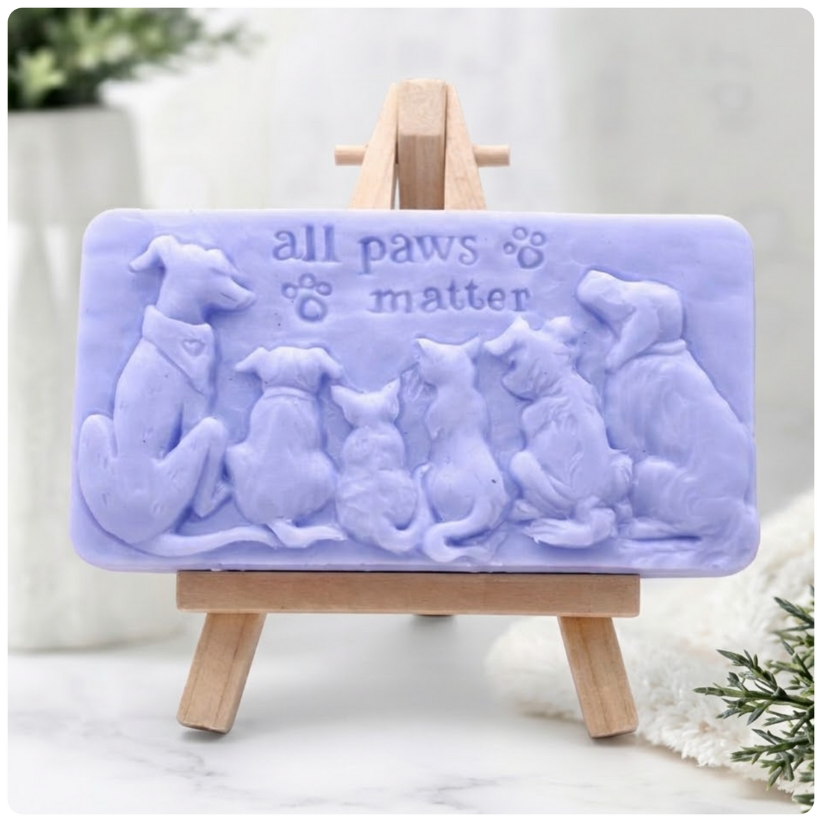 Handmade All Paws Matter vegan soap bar made with indigo powder and displayed on a wooden easel featuring an embossed pet design.