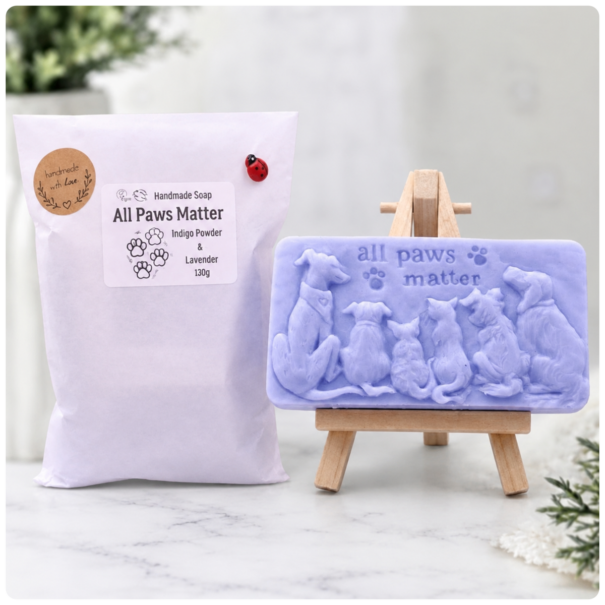 Handmade All Paws Matter vegan soap bar made with indigo powder and displayed on a wooden easel featuring an embossed pet design. Displayed with beautiful eco friendly packaging 