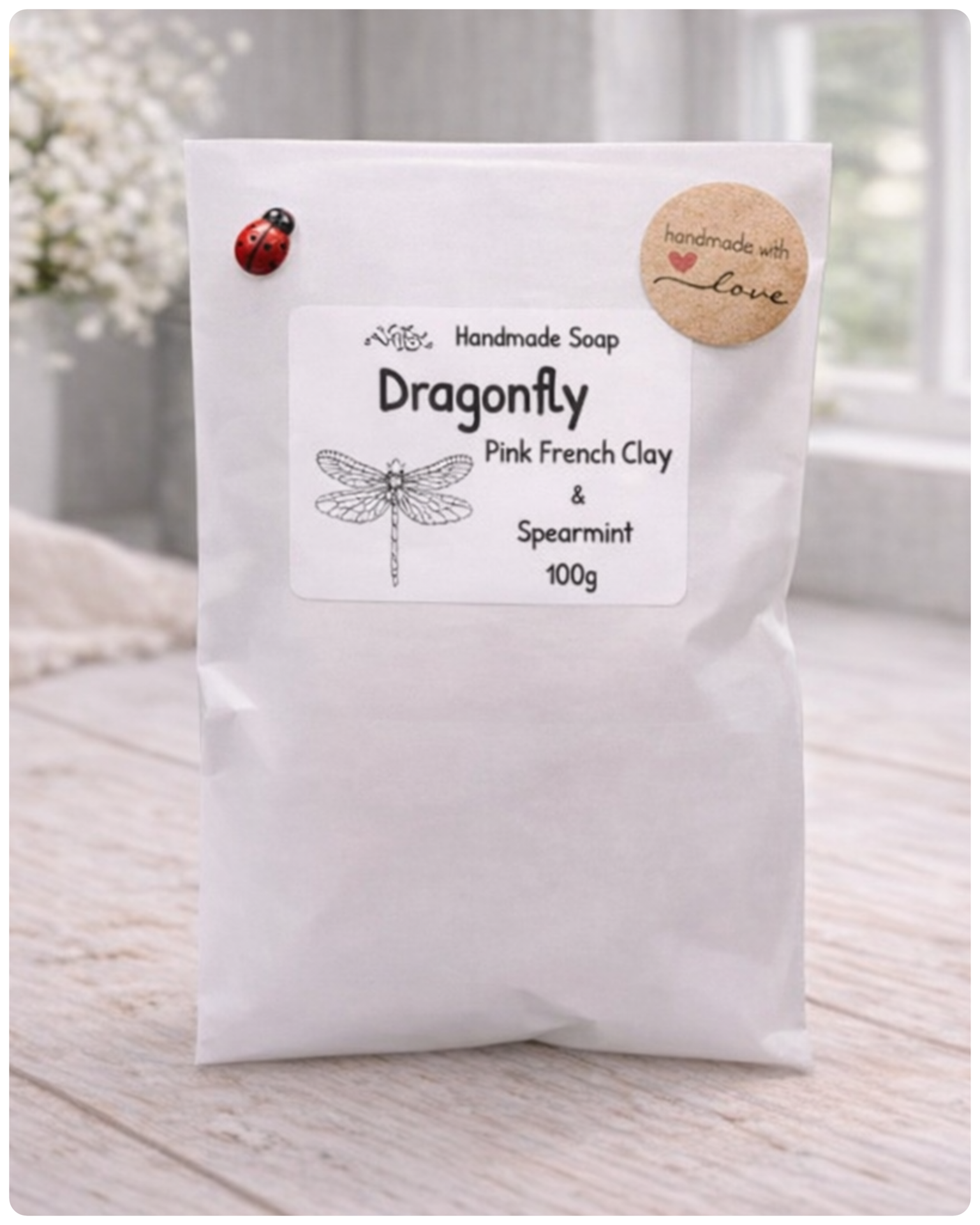 Handmade soap packaging with dragonfly design and text on a white background