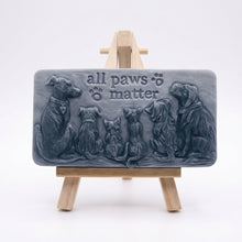 Load image into Gallery viewer, A rectangular handmade vegan soap bar gift, featuring a detailed relief carving of several dogs and a cat sitting together, with the words "all paws matter" and two paw prints embossed at the top, displayed on a wooden easel. Made in Blackpool.
