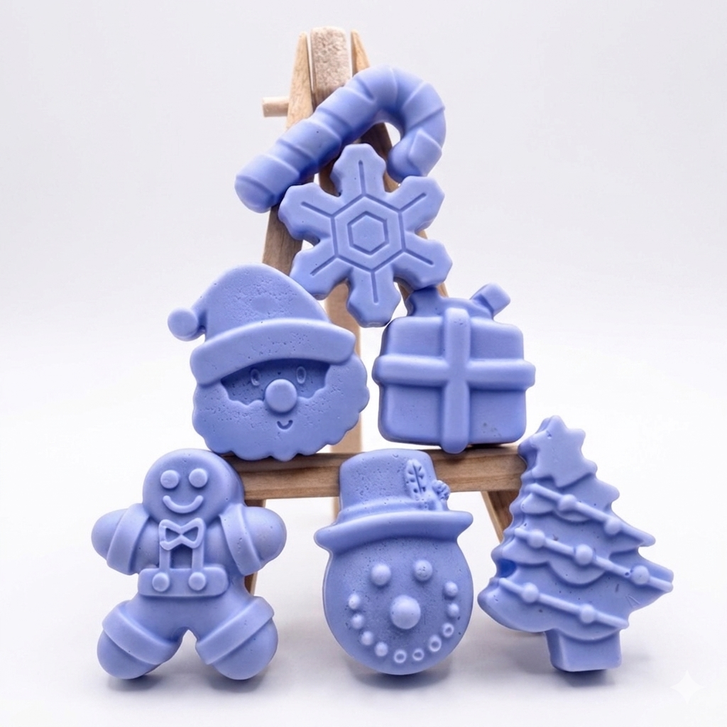 A collection of six handmade vegan Christmas soaps featuring a candy cane, snowflake, Santa Claus face, wrapped gift box, gingerbread man, snowman, and a decorated Christmas tree, arranged in a pyramid on a wooden stand.