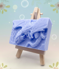 Load image into Gallery viewer, Dragon gift. Dinosaur gift. Our Flying Dragon soap features a striking dragon with its majestic wings spread wide, symbolising freedom and power. This artisan bar is vegan, cruelty-free, and designed with care for both your skin and the planet. Available in your choice of colour and essential oil. Each soap comes beautifully wrapped in eco friendly packaging. zero waste gift. kodern gift ideas. handmade home style. eco conscious home. eco friendly gifts. go green home. 
