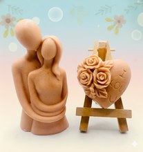 Load image into Gallery viewer, Two handcrafted vegan soaps, one in the shape of a couple embracing and another in the shape of a heart with 'I LOVE U' inscription, presented in a wooden display stand. Presented in beautiful eco friendly gift box with paper ribbon. 
