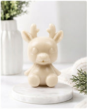 Load image into Gallery viewer, A 3D handmade vegan soap crafted into a cute, sitting baby reindeer with small antlers, rounded features, and a sweet expression, set against a bright farmhouse window.
