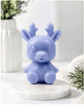 A 3D handmade vegan soap crafted into a cute, sitting baby reindeer with small antlers, rounded features, and a sweet expression, set against a bright farmhouse window.