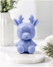 Load image into Gallery viewer, A 3D handmade vegan soap crafted into a cute, sitting baby reindeer with small antlers, rounded features, and a sweet expression, set against a bright farmhouse window.
