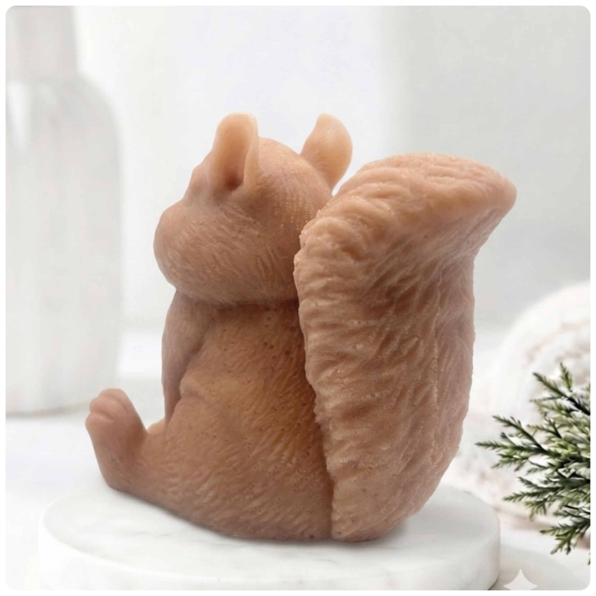 Handmade 3D squirrel-shaped soap sitting upright on a white marble display stand, featuring detailed textured fur and a bushy tail.