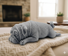 Load image into Gallery viewer, handmade vegan soap in the shape of a realistic sleeping pug dog lying flat, showing detailed wrinkles and fur texture, displayed in a spa-like setting with a candle and lavender.
