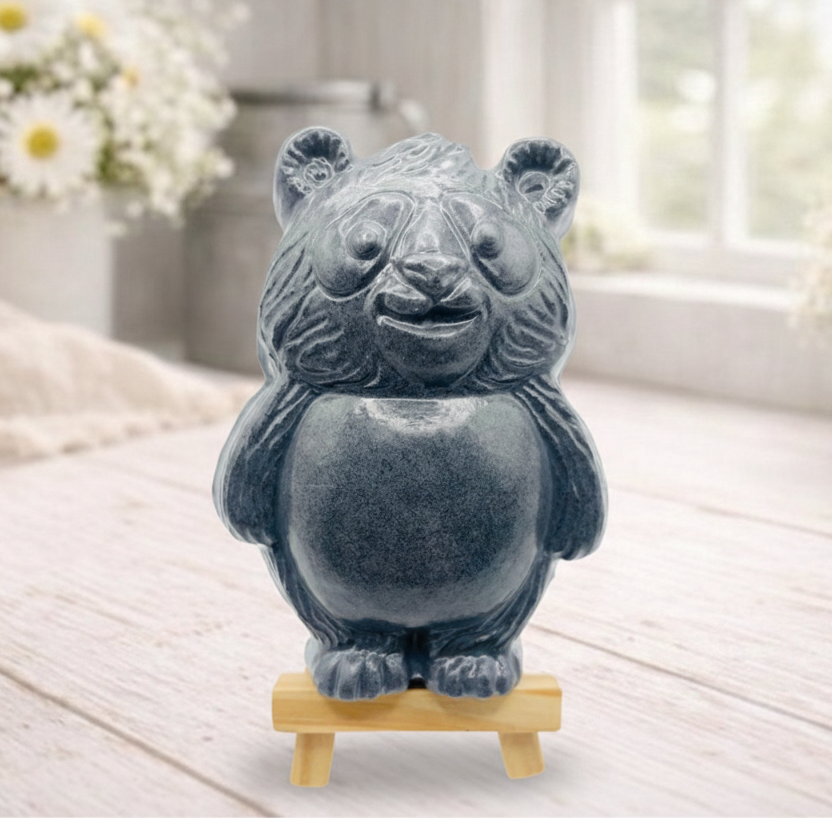 Handmade vegan soap sculpted in the shape of a round, sitting panda bear with detailed fur textures and a friendly expression, displayed on a small wooden easel.