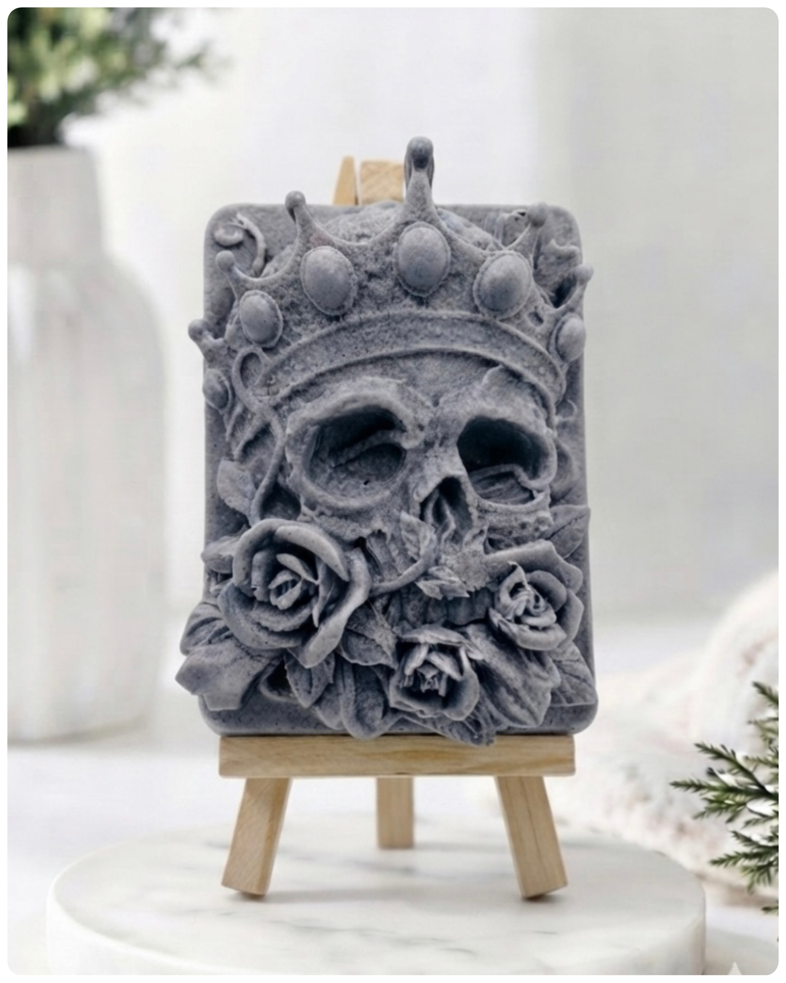 handmade vegan soap gift featuring a detailed relief of a skull wearing a crown, surrounded by a border of roses, displayed on a small wooden easel.