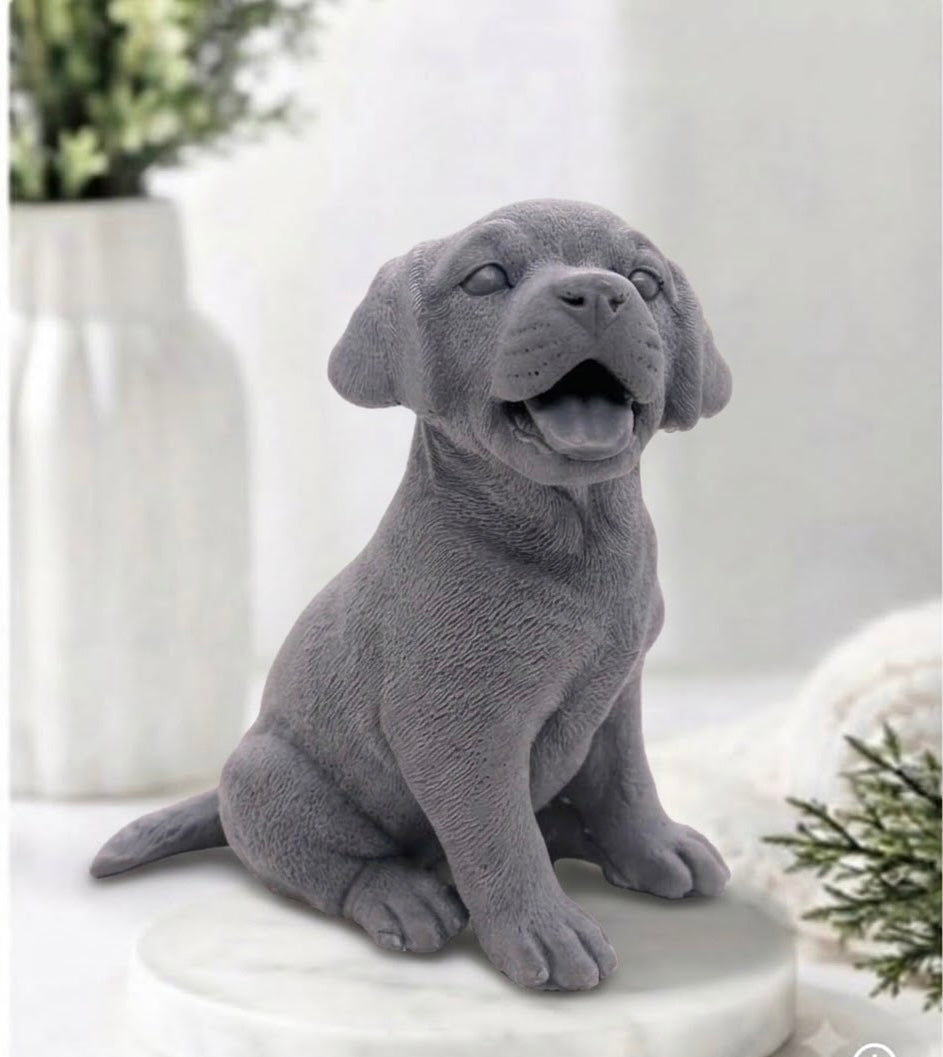 Front-facing view of a handmade activated charcoal, Labrador puppy dog vegan soap bar sitting with a happy, open-mouthed expression and detailed textured paws on a white tray.
