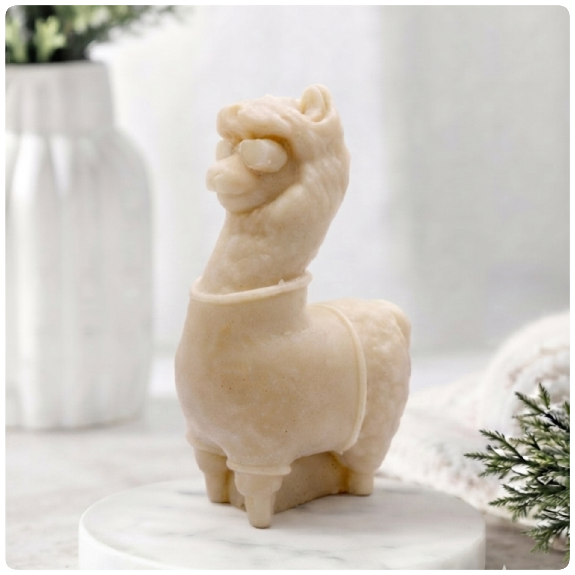 Decorative llama-shaped vegan soap on a white surface with a jar of lavender flowers in the background.