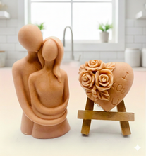 Load image into Gallery viewer, Two vegan soap sculptures, one shaped like a couple and the other with floral designs, with I love U imprinted on heart soap 
