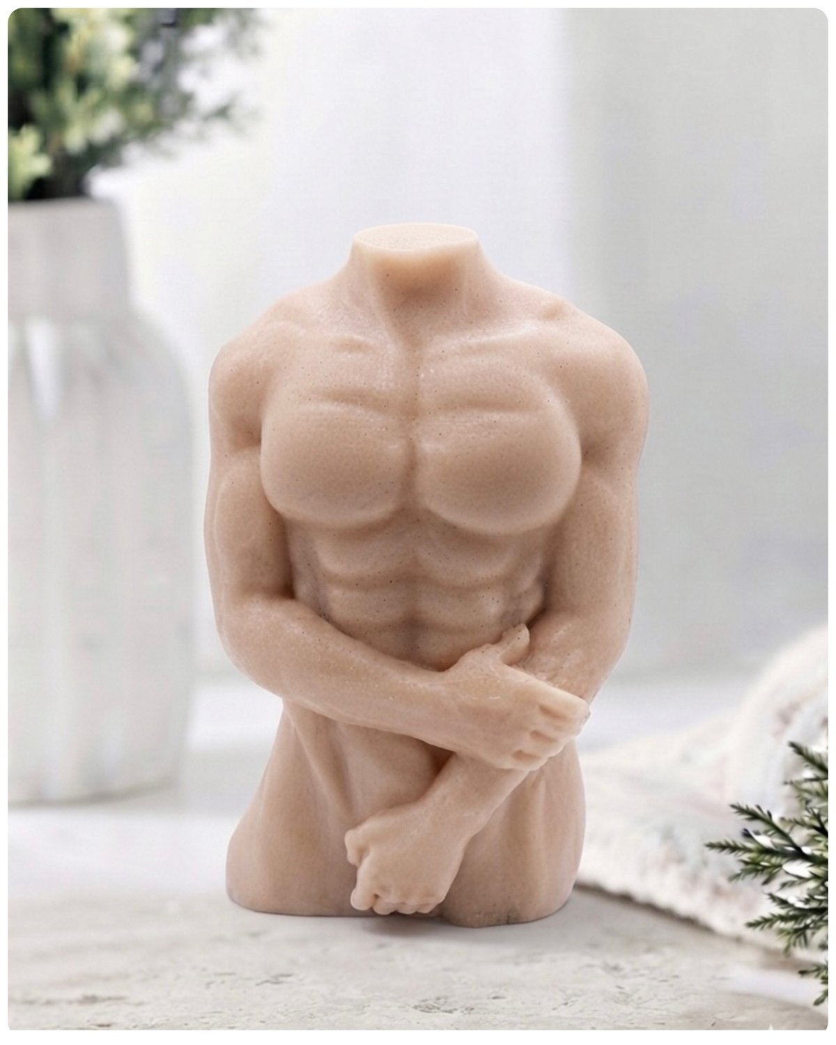 A highly detailed handmade vegan soap in the shape of a muscular male torso, featuring a detailed sculptural design, displayed against a whimsical background for a sophisticated farmhouse decor touch.