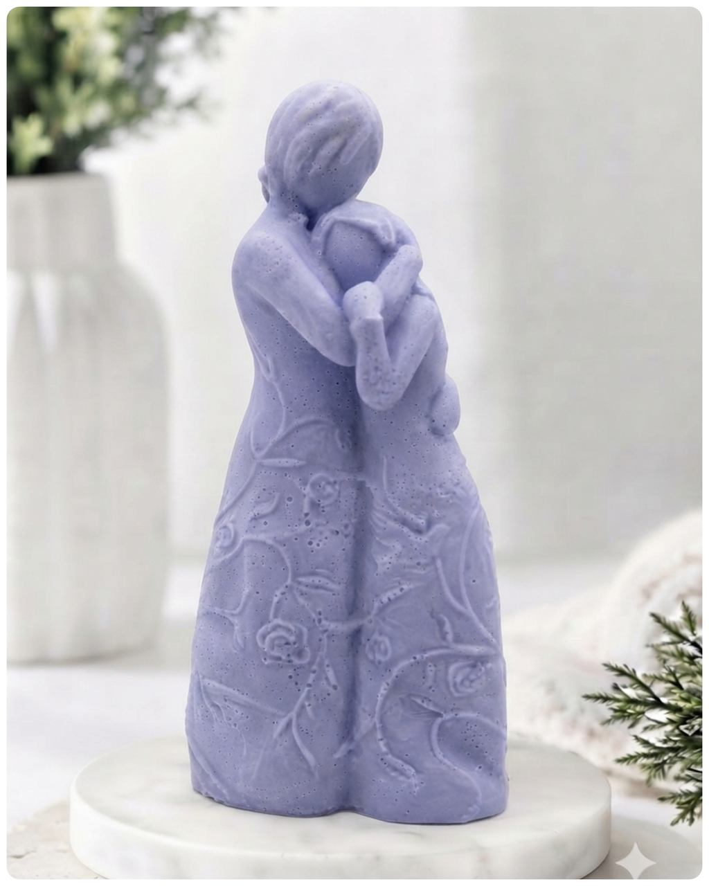 handmade vegan soap, sculpted as a mother and daughter in a tender standing embrace, featuring an intricate embossed floral and vine pattern on their dresses.