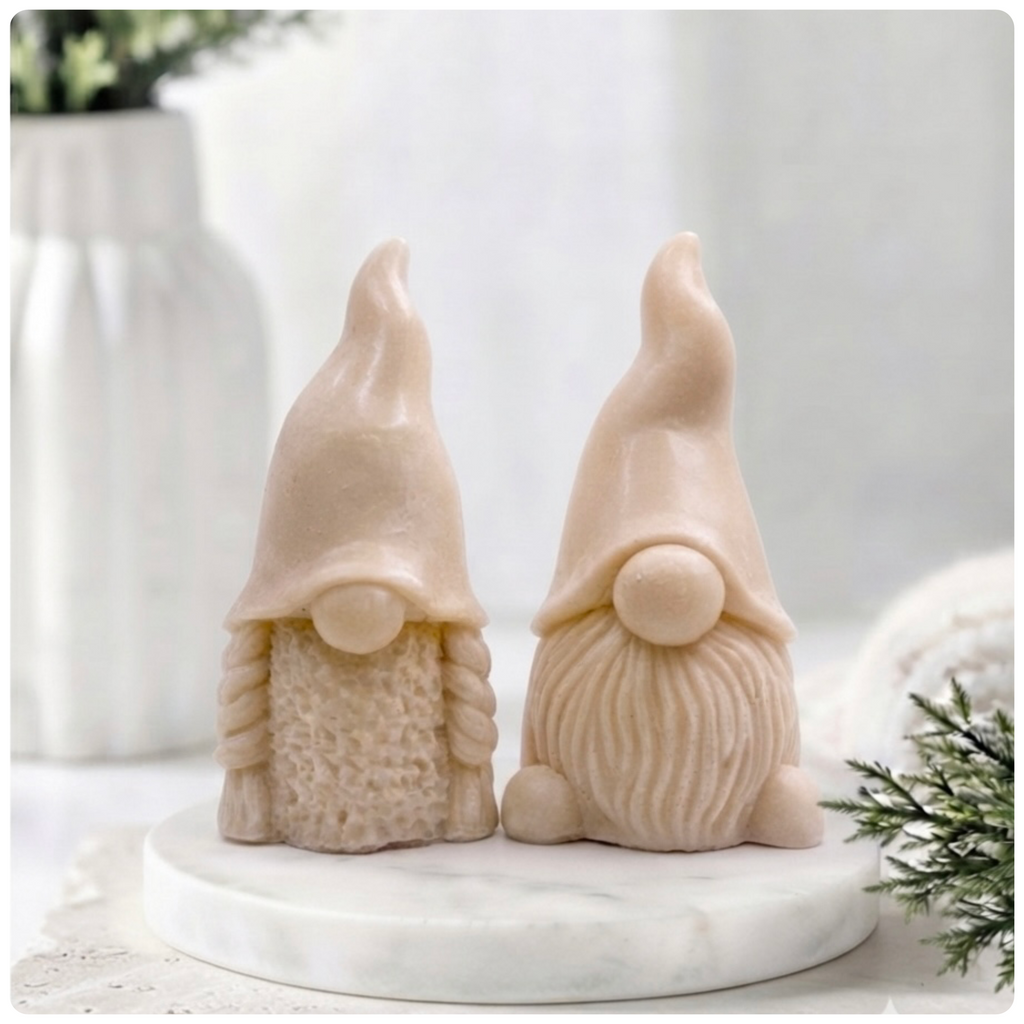 A pair of handmade vegan soaps, featuring a Mr and Mrs Gnome (gonk) set; one with a full textured beard and the other with thick braided plaits, both wearing tall, pointed hats. Gift boxed.
