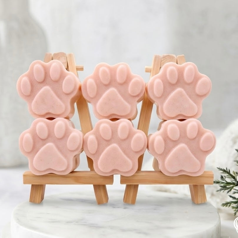 Six pink paw print-shaped soaps on a small wooden easel, on top of a marble stand.