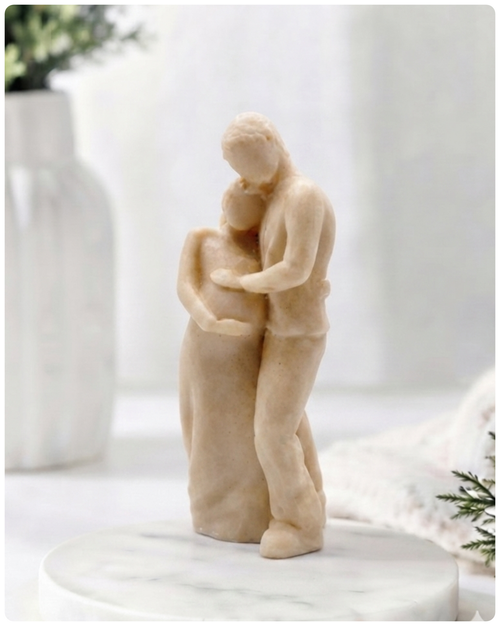 A 3D handmade vegan soap in a warm cream tone, sculpted into a standing figure of a pregnant couple; the partner stands behind the expectant mother, tenderly cradling her baby bump, displayed on a light wooden surface in a bright farmhouse setting.