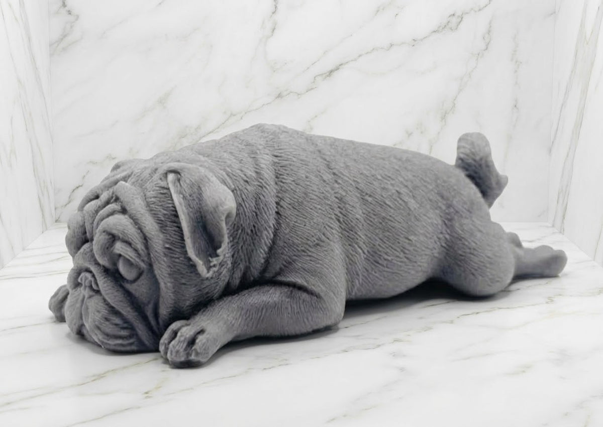 A charcoal grey pug-shaped vegan soap gift. resting on a light marble surface with a soft background.