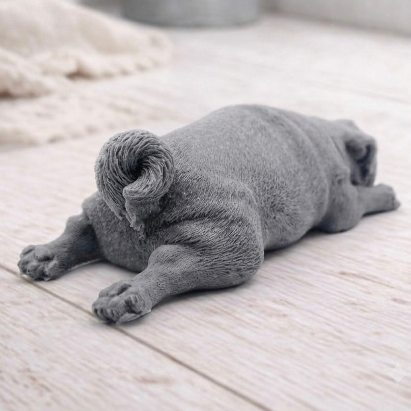A detailed handmade vegan soap gift, sculpted in the shape of a pug dog lying flat on its stomach in a sleeping position, showing realistic skin folds and fur texture
