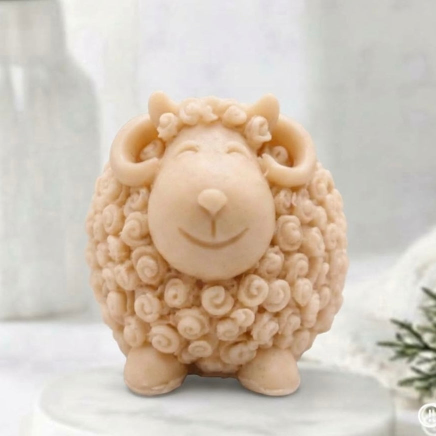 A soft yellow sheep / Ram soap with curly textured wool, closed eyes, and a smiling face, displayed on a white surface against a soft blurred background.