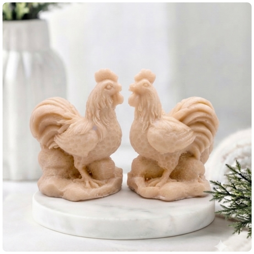 Two handmade vegan soaps sculpted in the shape of proud roosters (cockerels) with detailed feathers, combs, and curved tail feathers, standing on a rustic base, in a natural  colour. gift boxed.