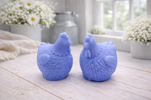 Load image into Gallery viewer, Two handmade vegan soaps in the shape of plump, realistic chicken sculptures with detailed feather textures, displayed on a rustic white wooden surface in a bright farmhouse decor setting.
