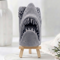 A 3D handmade vegan soap sculpted into a realistic great white shark head with its jaws wide open to reveal multiple rows of sharp teeth, displayed on a miniature wooden easel in a bright farmhouse setting.