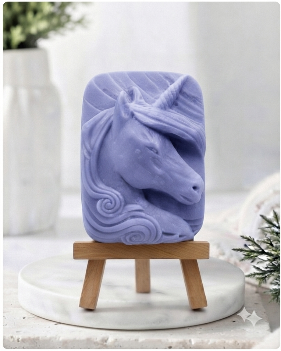 handmade vegan soap featuring a detailed unicorn head relief with a spiralled horn and flowing curly mane, displayed on a small wooden easel in a bright farmhouse decor setting.
