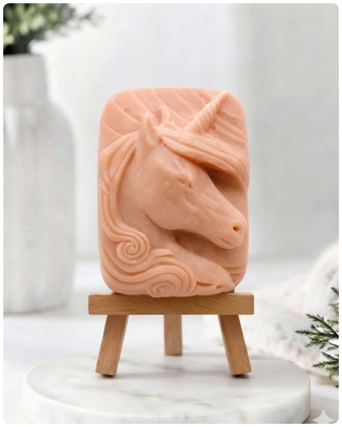 handmade vegan soap featuring a detailed unicorn head relief with a spiralled horn and flowing curly mane, displayed on a small wooden easel in a bright farmhouse decor setting.