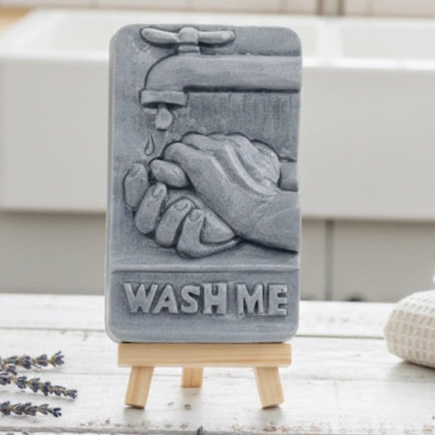 Gray soap with hands and faucet design on a stand, with 'Wash Me' text imprinted on soap 