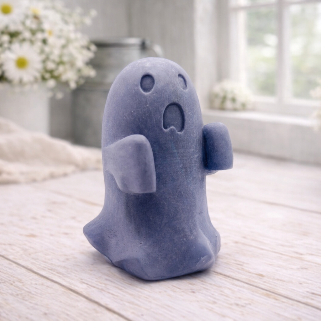 Handmade vegan soap ghost gift with a surprised expression, displayed on a light timber surface with soft white daisies in the background.
