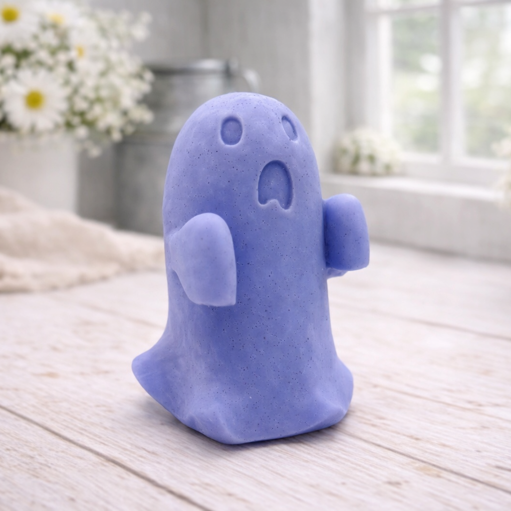 Handmade vegan soap ghost gift with a surprised expression, displayed on a light timber surface with soft white daisies in the background.
