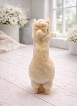 Load image into Gallery viewer, handmade vegan soap in the shape of a realistic standing alpaca or llama sculpture, featuring a smooth body with detailed fur texture on the head and neck, displayed in a bright farmhouse decor setting.
