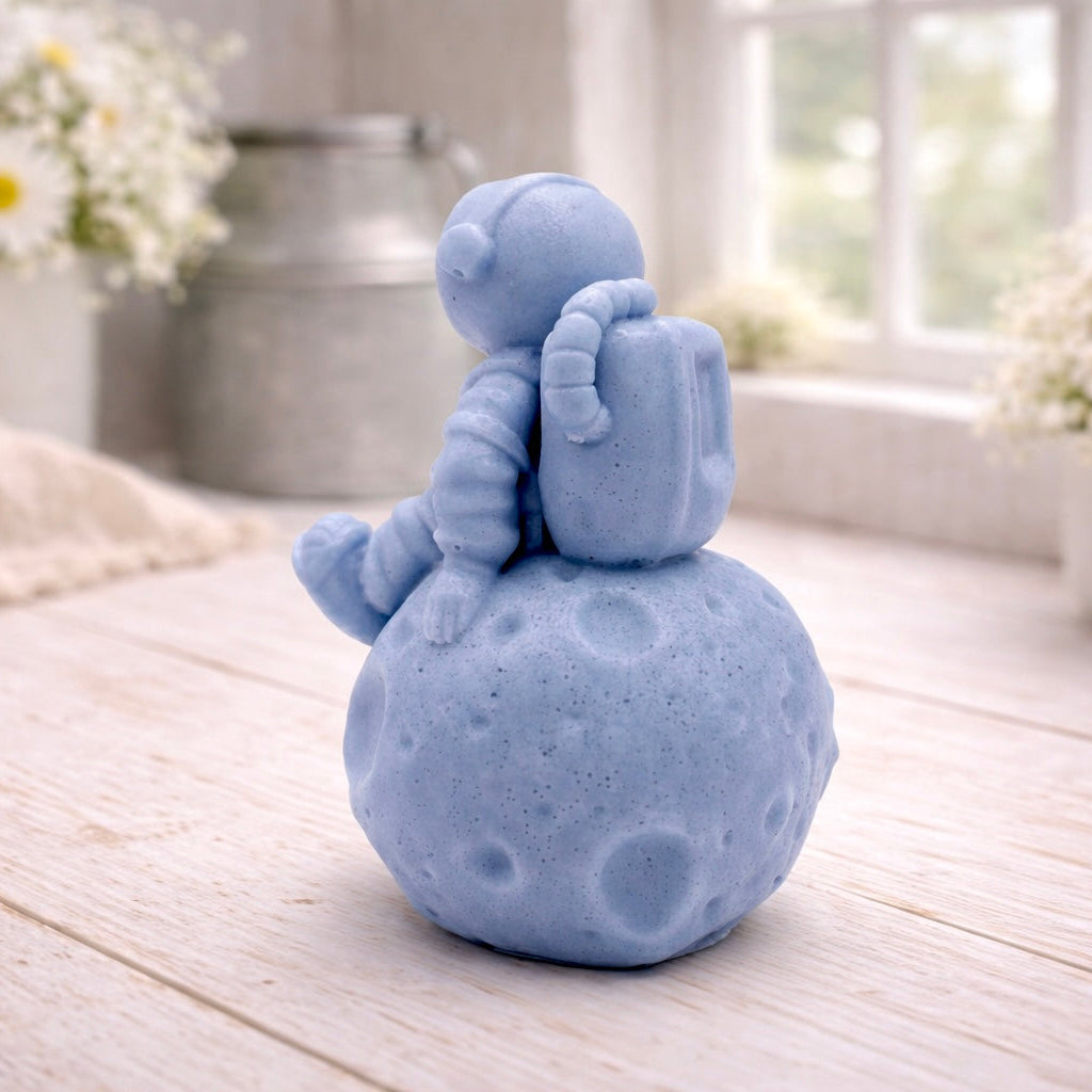 handmade vegan soap in the shape of a realistic astronaut sculpture sitting on the moon, featuring detailed spacesuit textures and craters on the lunar surface, displayed in a bright farmhouse decor setting.
