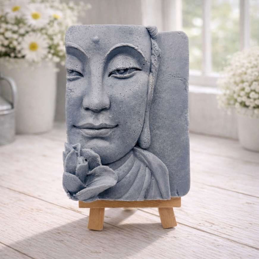 handmade vegan soap featuring a serene Buddha face relief with a lotus flower, displayed on a small wooden easel in a bright farmhouse decor setting with flowers and a rustic milk churn.