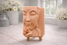 Load image into Gallery viewer, handmade vegan soap featuring a serene Buddha face relief with a lotus flower, displayed on a small wooden easel in a bright farmhouse decor setting with flowers and a rustic milk churn.
