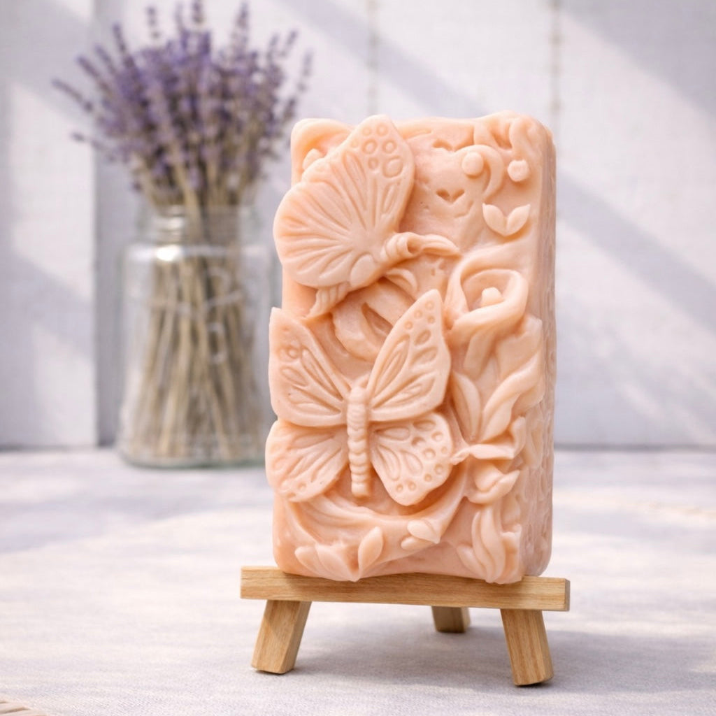 handmade vegan soap featuring a detailed 3D relief of butterflies and flowers, displayed on a wooden easel against a rustic farmhouse decor background with lavender.