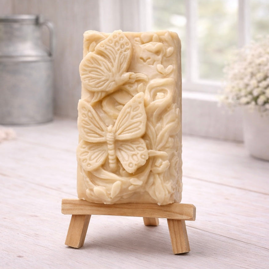 Decorative yellow French clay soap with butterfly design on a wooden stand in a bright room.