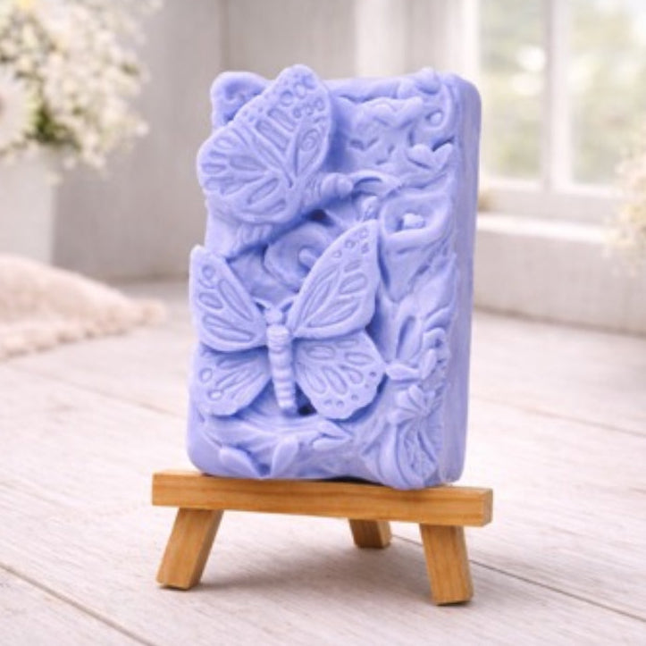 Blue soap bar with butterfly design on a wooden stand in a bright room.