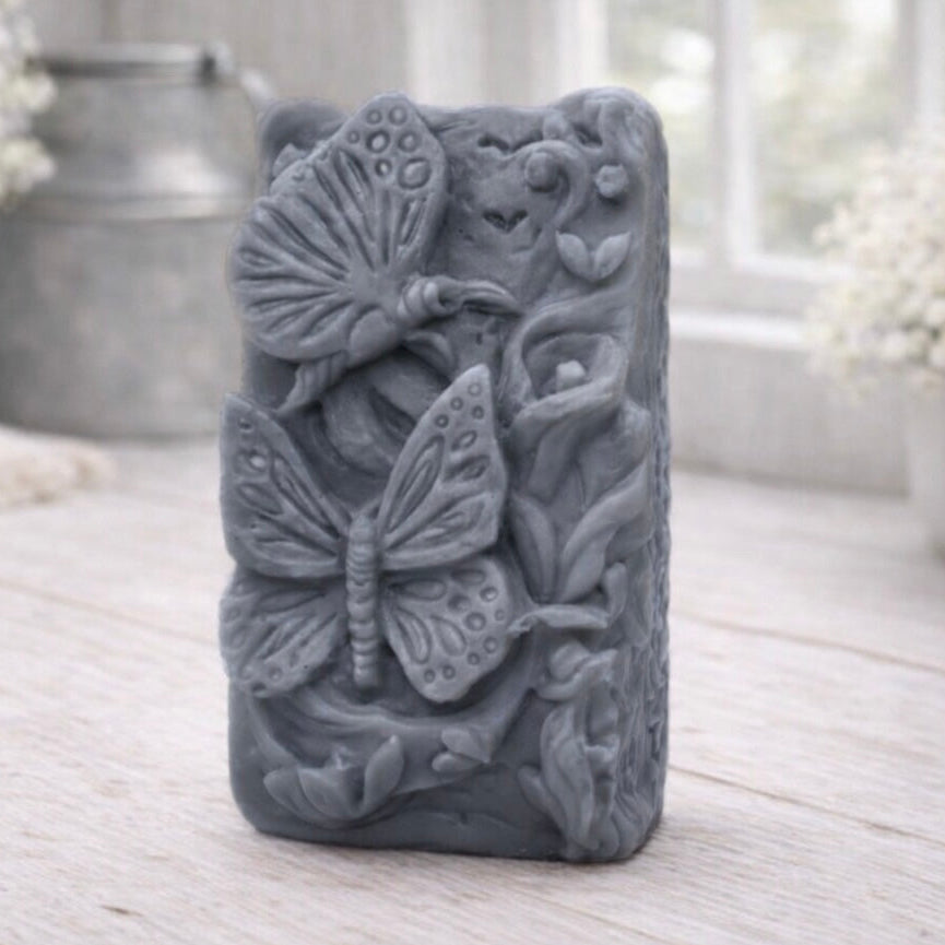 Decorative vegan soap with butterfly and floral patterns on a wooden surface.