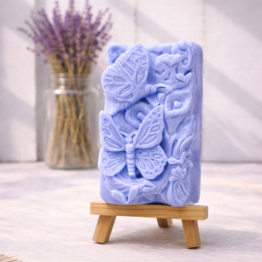 handmade vegan soap featuring a detailed 3D relief of butterflies and flowers, displayed on a wooden easel against a rustic farmhouse decor background with lavender.