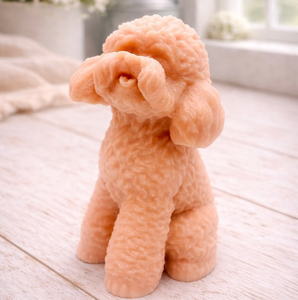 handmade vegan soap in the shape of a realistic sitting cockapoo or poodle sculpture, featuring detailed curly fur texture and a classic poodle groom, displayed on a rustic white wooden surface in a bright farmhouse decor setting.