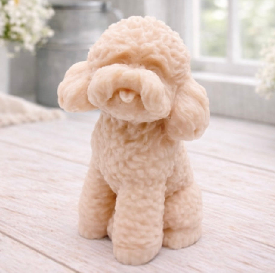 handmade vegan soap in the shape of a realistic sitting cockapoo or poodle sculpture, featuring detailed curly fur texture and a classic poodle groom, displayed on a rustic white wooden surface in a bright farmhouse decor setting.