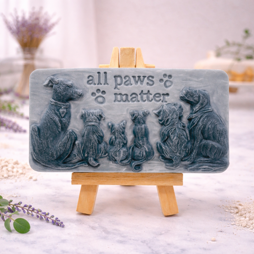 handmade vegan soap featuring a detailed 3D relief of various dog breeds sitting in a row with the text "all paws matter," displayed on a wooden easel against a rustic farmhouse decor background.