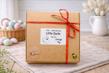 Load image into Gallery viewer, Gift box with 'Little Ducks' label and red ribbon on a wooden surface.

