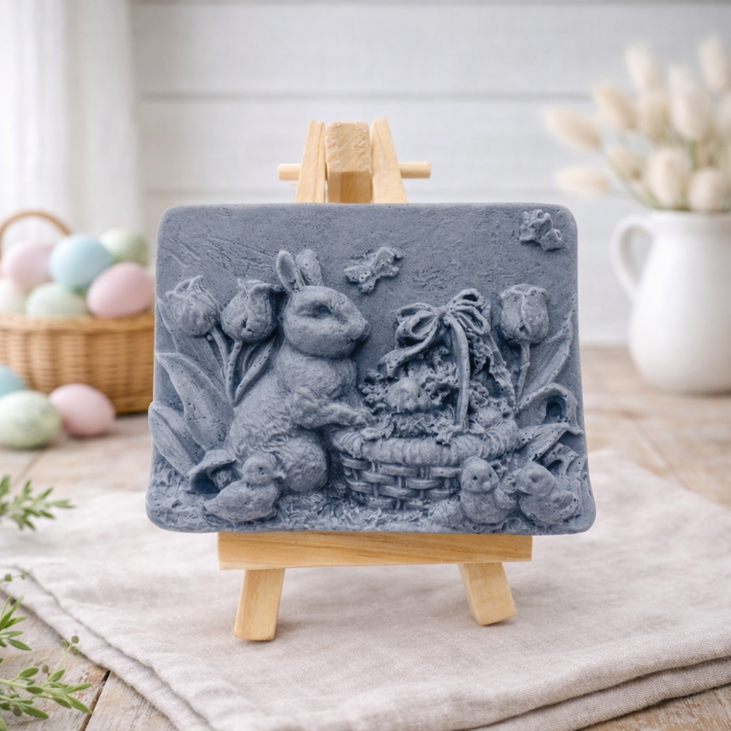 handmade vegan soap featuring a highly detailed 3D relief of a rabbit in a garden with tulips and an Easter basket, displayed on a wooden easel in a rustic farmhouse decor setting.